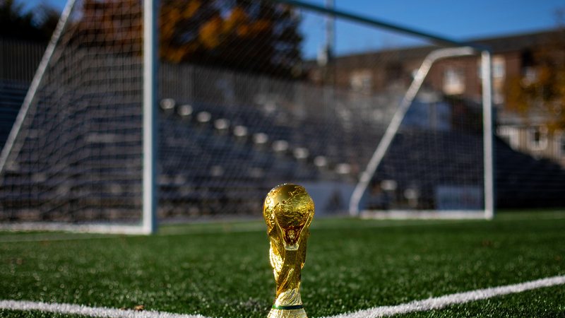 A corrida da Seleção Brasileira pelo hexa chega na fase de "mata-mata" Brasil entra em campo nesta segunda (5) em busca da vaga nas quartas-de-final da Copa Réplica da taça da Copa do Mundo em gramado de futebol, em frente à trave - Unsplash