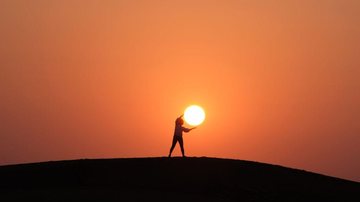 Tem feito um sol para cada um nos últimos dias! Veja seis cuidados que você precisa ter em dias quentes Foto de por do sol em que pessoa parece estar segurando o sol - Unsplash