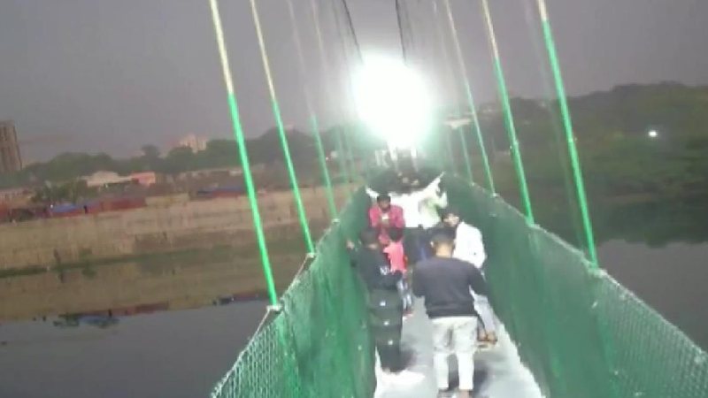 Algumas pessoas na ponte antes da estrutura ceder e derrubá-las em um rio na Índia Ponte suspensa Pessoas em uma ponte - Reprodução