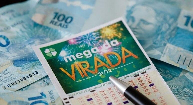 A Mega-Sena da Virada não acumula. Se ninguém acertar as seis dezenas, o prêmio será dividido entre os que acertarem cinco números Bolada da Mega-Sena da Virada sobe para R$ 500 milhões Volante da Mega-Sena da Virada e cédulas de R$ 100 - André Melo Andrade/ Estadão Conteúdo