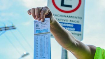 Na Zona Azul, o cartão para o estacionamento regulamentado custa R$3,00 por hora Zona Azul Pessoa segurando um papel de Zona Azul - Divulgação/Prefeitura de Bertioga