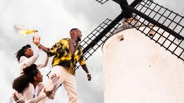 Capa do novo álbum de Djonga 'O dono do lugar' lançado em diversas plataformas nesta quinta-feira (13) Djonga Homem em um moinho de vento junto com duas mulheres segurando uma tocha - Reprodução