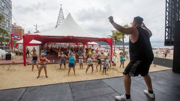 Instrutores de dança animam as pessoas e sobem ao palco para comandar os presentes às 10h, 14h, 16h e 17h Estação Verão Praia Grande Homem coreografando danças para outras pessoas na praia - Divulgação