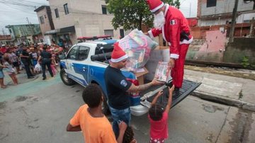 Entregas aconteceram em comunidades carentes do município de Praia Grande Papai Noel Papai Noel em cima de uma viatura da GCM entregando presentes para crianças - Divulgação