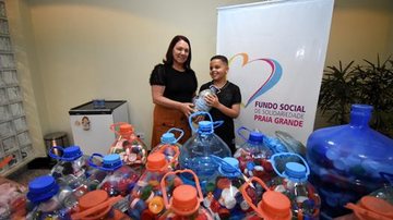 Todo o material arrecadado será será utilizado pela campanha que troca os itens por cadeiras de rodas que, de acordo com a prefeitura, ficam à disposição da população Doações Menino com doações em frente a um banner do Fundo Social de Solidariedade - Divulgação