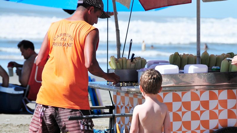 A prefeitura ressalta que serão concedidas 553 licenças e todas terão validade até o dia 28 do mês de fevereiro de 2023 Ambulante Ambulante na praia dando um milho para uma criança - Divulgação