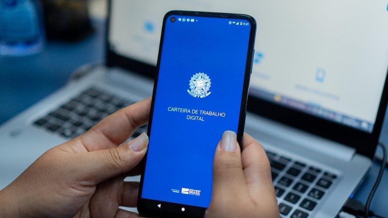 Há diversas vagas atualmente no PAT da cidade de Guarujá Oportunidade Pessoa segurando o celular e abrindo o aplicativo da Carteira de Trabalho digital - Divulgação/Prefeitura de Bertioga
