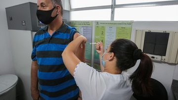 As vacinas estarão disponíveis nas 30 Usafas da cidade Praia Grande inicia campanha de vacinação contra a gripe terlça-feira (11) Idoso recebendo dose de vacina no braço, aplicada por enfermeira - Prefeitura de Praia Grande