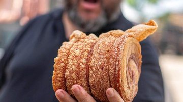 Torresmo de rolo é uma das iguarias que vão ser possíveis degustar no Torresmofest de Praia Grande Festival do Torresmo chega no Litoral Plaza Shopping, em Praia Grande Homem segurando torresmo de rolo - Divulgação