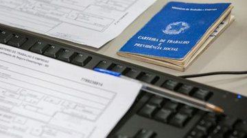 Os documentos e os pré-requisitos para cada oportunidade são indispensáveis Emprego Teclado de computador, com papeis em cima e ao lado, uma caneta e uma carteira de trabalho - Divulgação