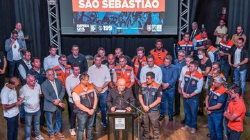 Políticos reunidos para falar sobre a calamidade pública de São Sebastião Lula em São Sebastião Homens juntos em cima de um palanque com microfone próximo - Reprodução/Twitter