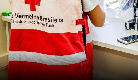 Doações financeiras devem ser enviadas por meio do Pix da Cruz Vermelha de SP: soschuvas@cruzvermelhasp.org.br Cruz Vermelha de SP Pessoa de costas com o uniforme da Cruz Vermelha de SP - Divulgação