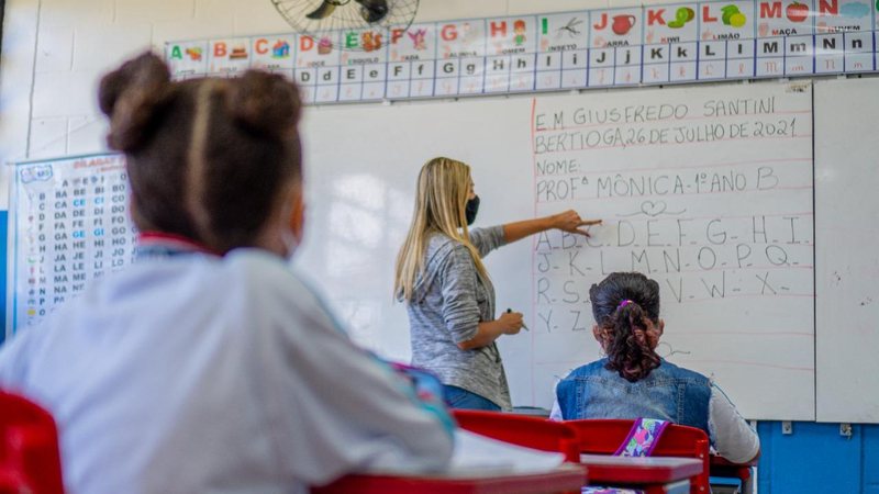 Os pais devem ficar atentos e busquem informações sobre o calendário escolar Aula Professora explicando matéria na lousa e alunos prestando atenção - Divulgação/Prefeitura de Bertioga