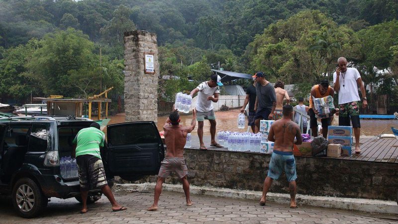 População recebe doações de água mineral nos abrigos em São Sebastião Água mineral em São Sebastião Homens carregando caçamba de carro com fardos de água mineral e doações de mantimentos - Rovena Rosa/Agência Brasil