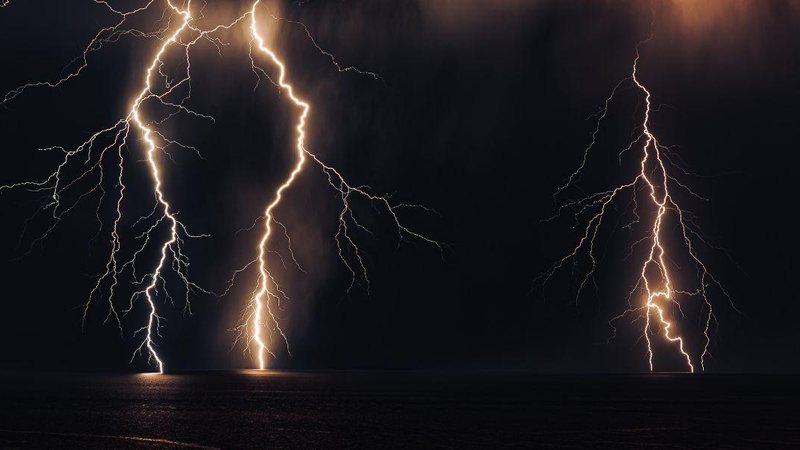 Alerta é válido deste sábado (4) até terça-feira (7) Defesa Civil emite alerta de chuvas fortes para a Baixada Santista e Litoral Norte de SP Descargas elétricas em céu noturno sobre o mar - Canva