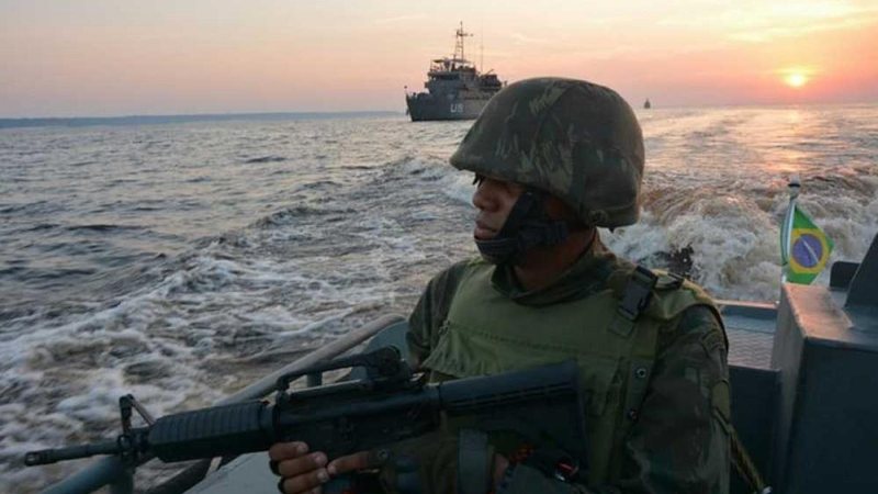 Fuzileiros navais voltarão a operar na região de Santos Fuzileiros navais reforçarão a segurança em Santos Soldado fuzileiro naval em embarcação olhando para o mar, com pôr do sol ao fundo - Marinha do Brasil