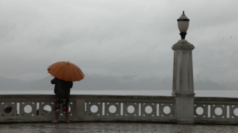 Prepare o guarda-chuva que o sábado (30) promete ser molhado no litoral paulista! Frente fria traz chuva para o último fim de semana de julho no litoral de SP Homem com guarda-chuva observa o mar em Santos - Francisco Arrais/Prefeitura de Santos
