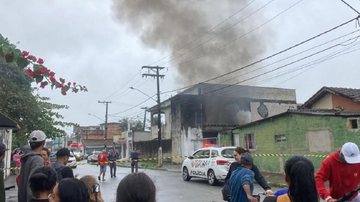 Ninguém se feriu gravemente, mas residência ficou com cômodos destruídos Crianças jogam bombinha e incendeiam residência em Guarujá Casa em chama com pessoas observando à distância - Imagem: Reprodução