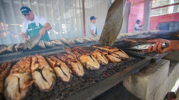 O cardápio conta com uma tainha na brasa, acompanhada de farofa com camarão, arroz e vinagrete, servindo bem duas pessoas Festa da Tainha de Praia Grande começa na sexta-feira (30) Tainhas na brasa sendo preparadas - Divulgação/Prefeitura de Praia Grande