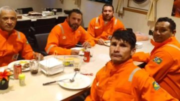 Cinco tripulantes foram resgatados. Três continuam desaparecidos Resgatados cinco tripulantes de barco pesqueiro que naufragou em Santa Catarina Homens abatidos em uma mesa - Imagem: Reprodução