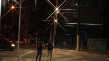A instalação começou nas avenidas da orla, nos pontos onde existem as faixas vivas  Dois homens atravessando a faixa de pedestres iluminada. - Por Francisco Arrais