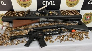 Na residência do suspeito foram encontradas três carabinas, uma garrucha e um revólver, além de mais de 2,6 mil munições de arma de fogo Suspeito de gerenciar venda de armas para criminosos em Itanhaém é preso Armas e munições apreendidas em Itanhaém - Polícia Civil