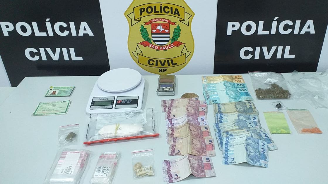 Drogas e dinheiro com banner da polícia civil ao fundo