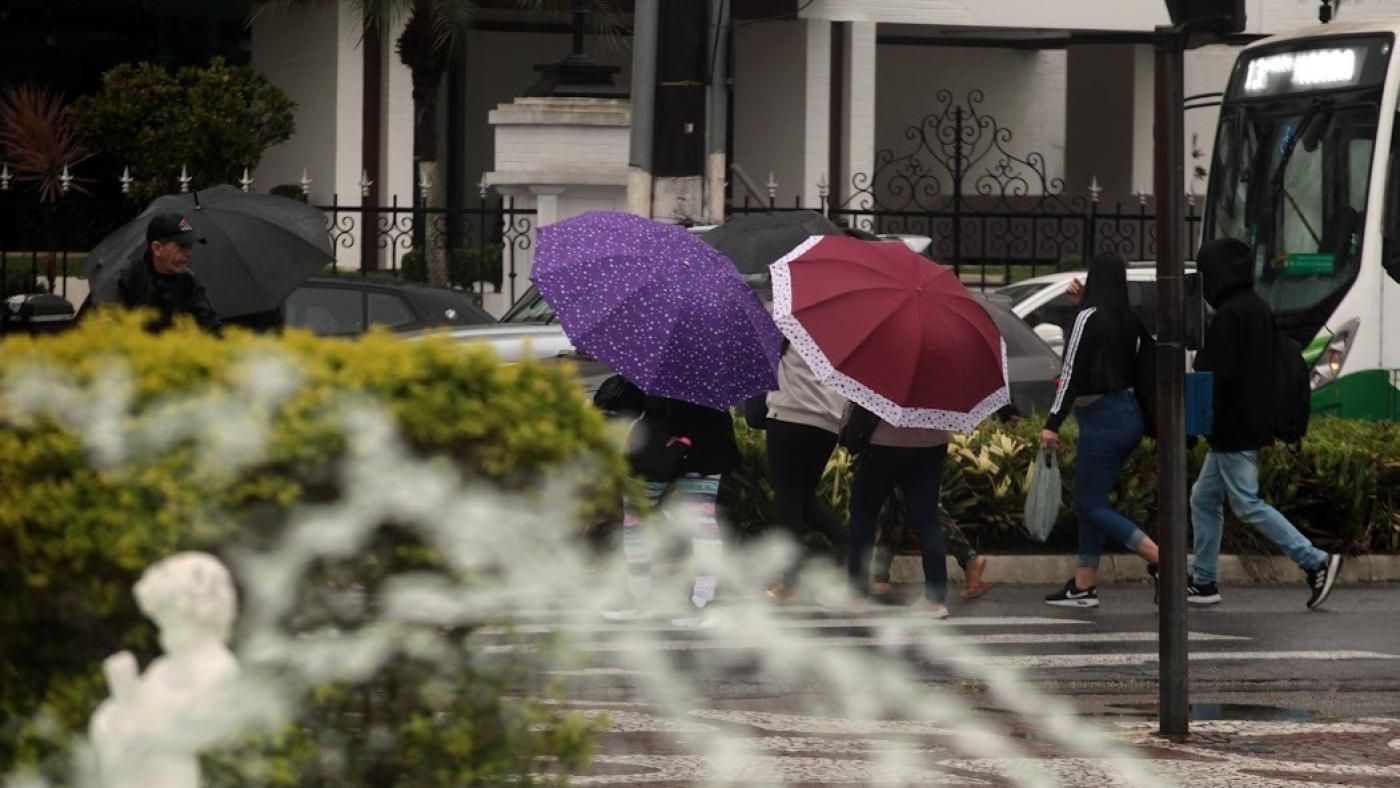 Pessoas com guarda chuvas em Santos