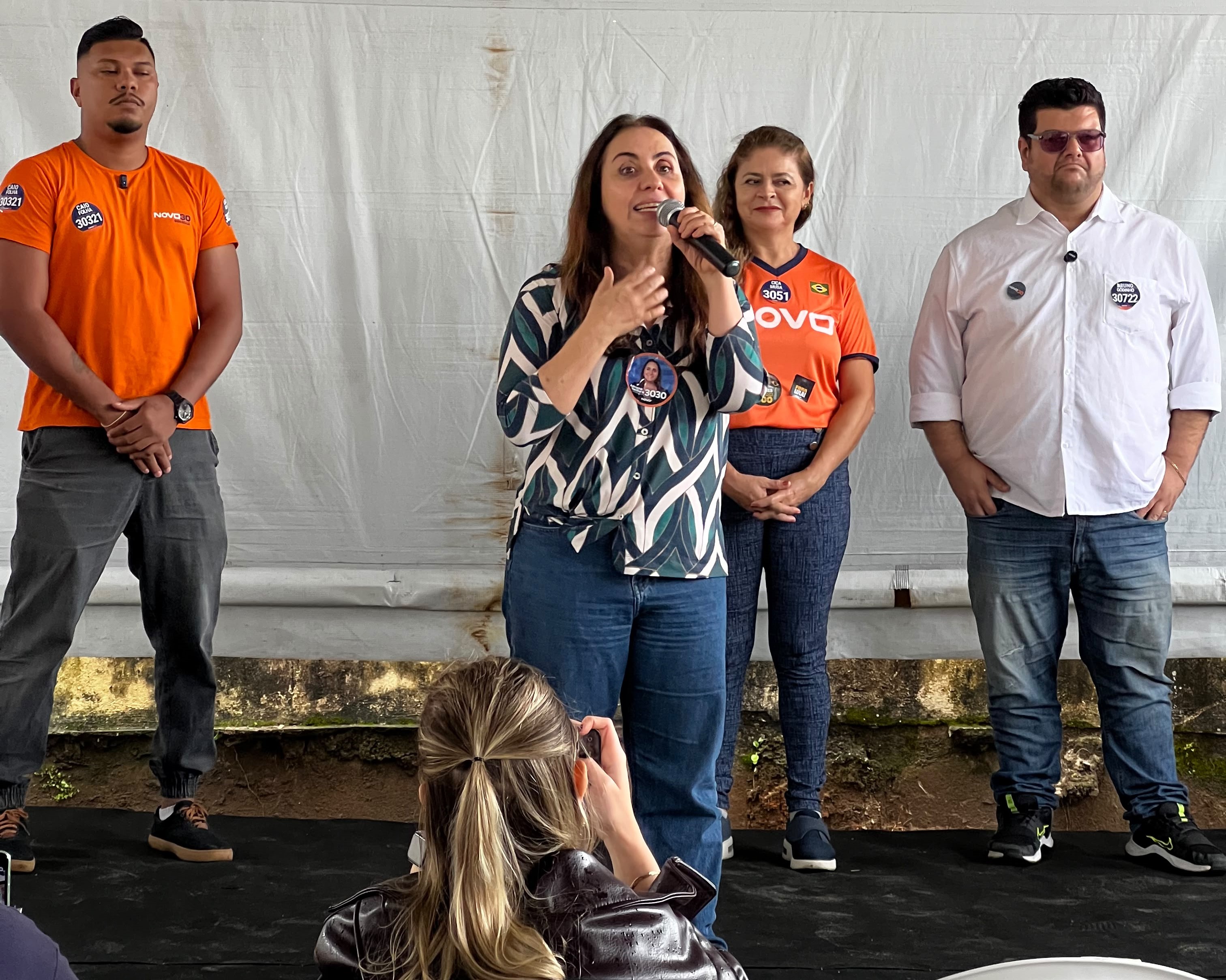 Mulher em cima de palco com microifone na mão