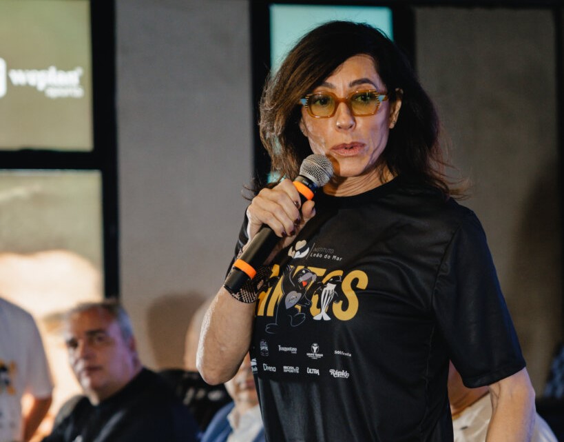 Imagem de mulher de óculos e falando ao microfone